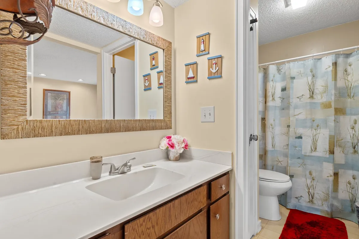 A cheerful bathroom scene with a decorative mirror, modern sink, and a shower curtain in floral designs. Pops of color in the wall art and accessories create a fresh, uplifting mood ideal for morning or evening routines.