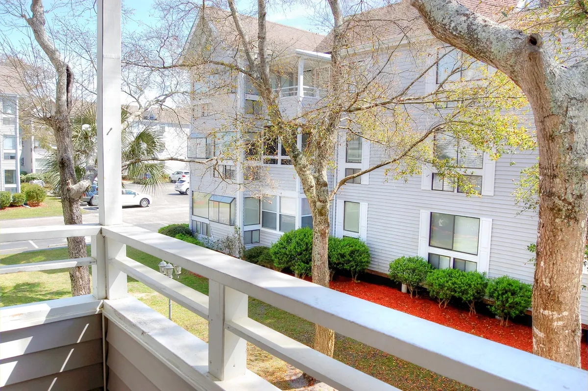 A tranquil view from the private balcony, featuring its railing, lush greenery, and the building facade beyond. The scene suggests enjoying peaceful moments outdoors, with room to sip coffee or take in the manicured resort grounds.